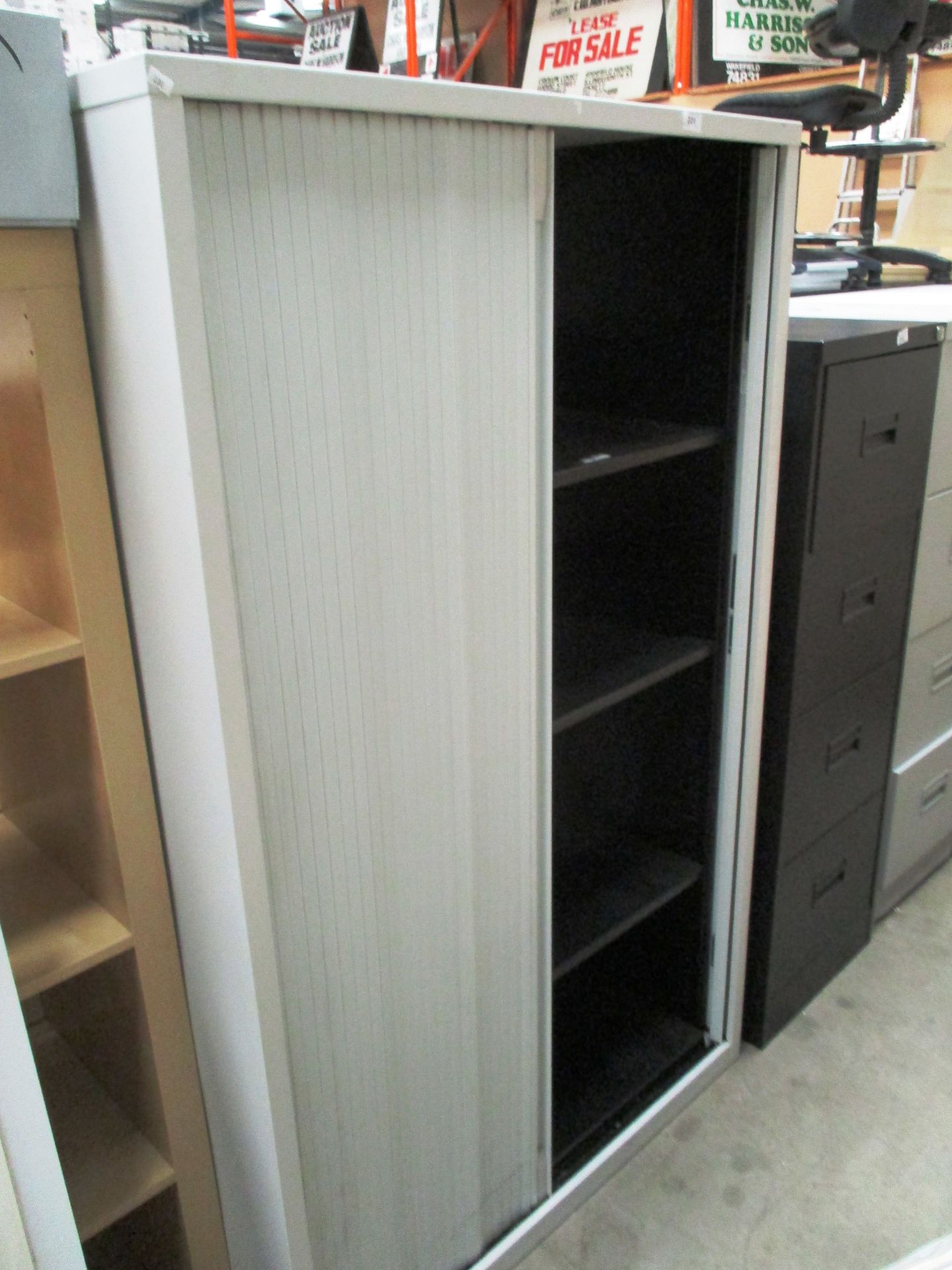 A grey metal tambour front stationary cabinet
