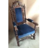 An elaborate carved wooden arm chair with blue velvet cushion, back and arm pads.