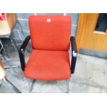 A burnt orange upholstered reception armchair on chrome frame