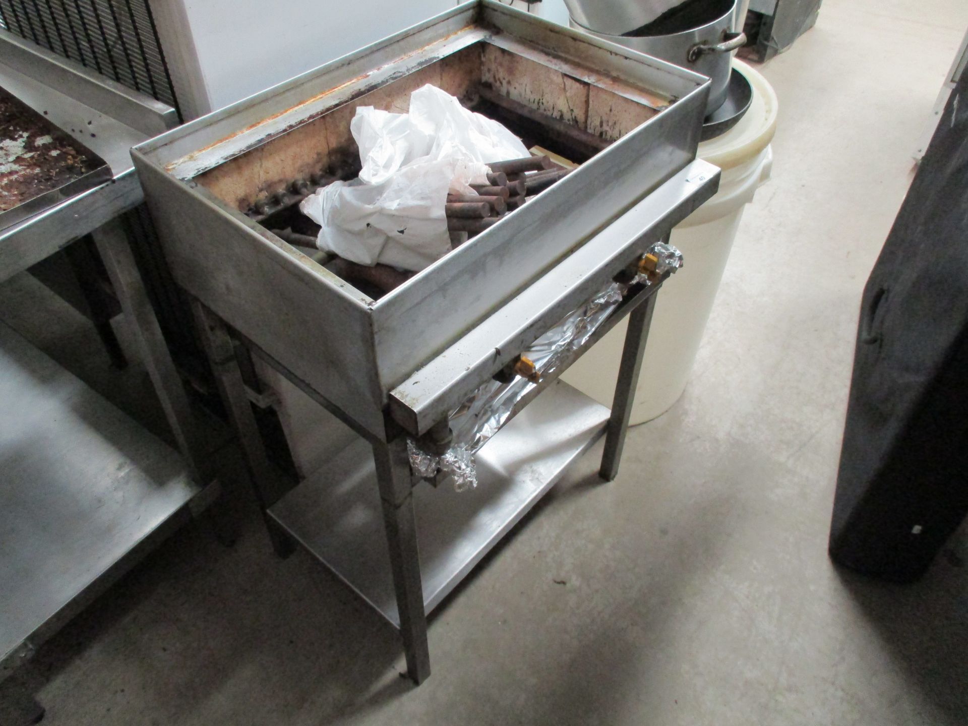 A stainless steel commercial flame gas grill on a stand