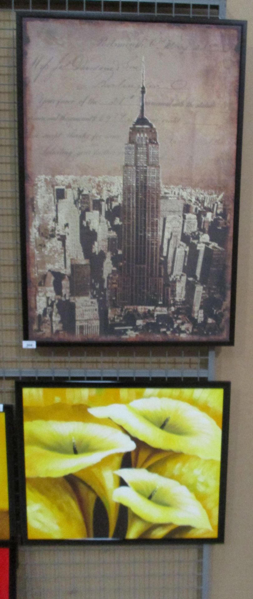 A large framed print of the Empire State Building and a framed print of yellow lilies