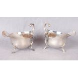 A pair of cyma-edge sauce boats of large proportion, leaf scroll handles, stepped hoof feet,