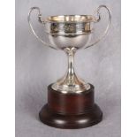 A two-handled circular section sports trophy "The Shaw Cup" spreading circular base,