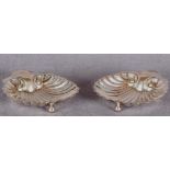 A pair of shell butter dishes each on three ball feet, matching pair of butter knives,