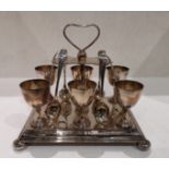 A plated six piece egg cup and spoon stand