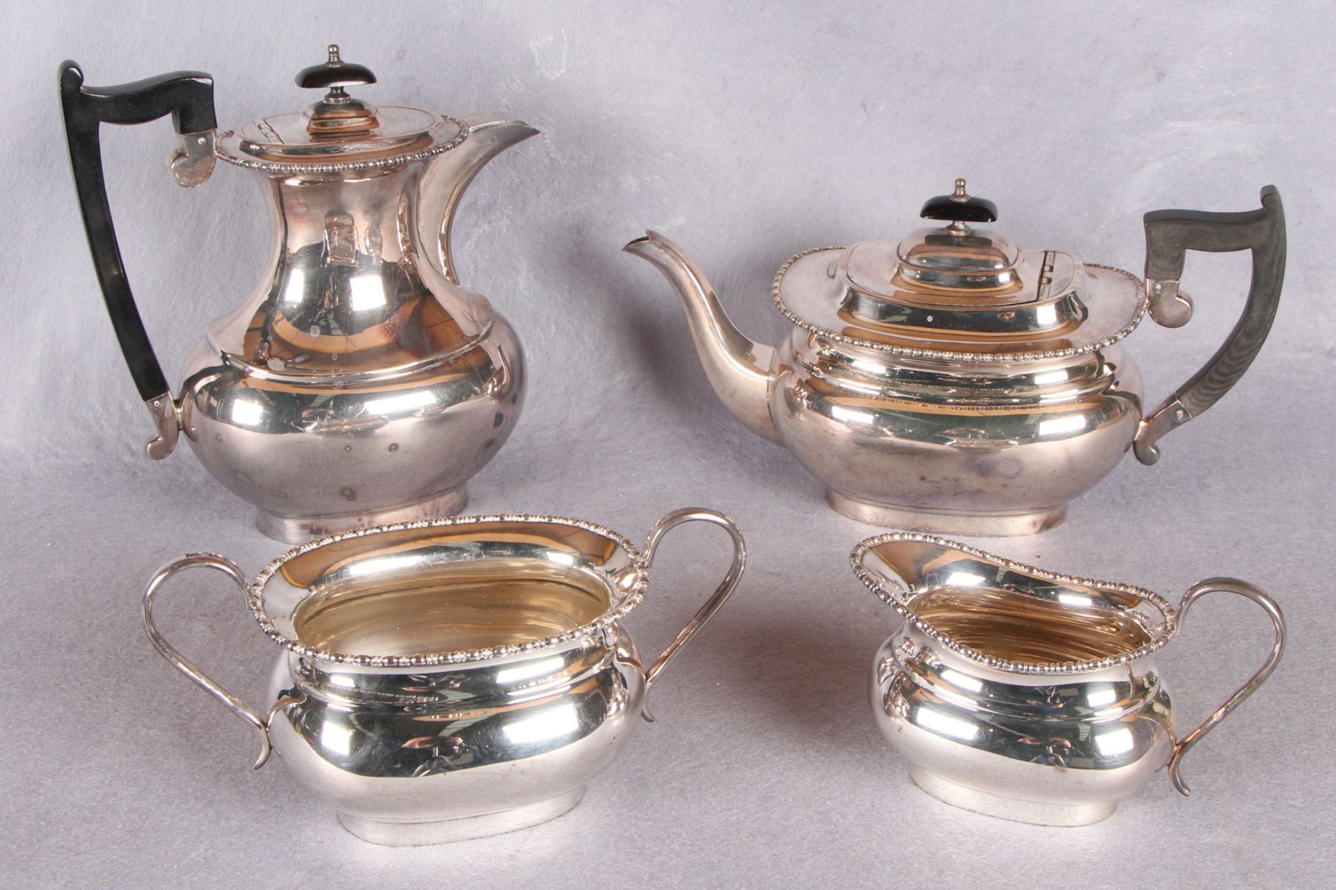 A four piece tea service, of rounded rectangular form, beaded borders,