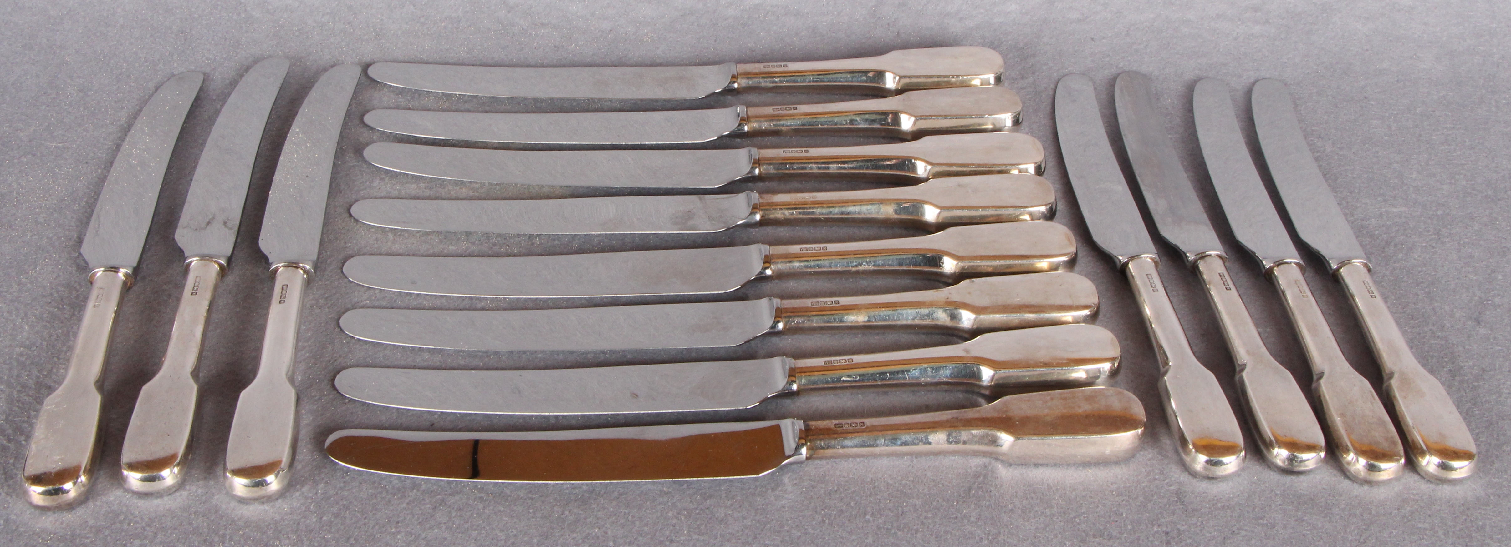 A set of eight silver handled table knives with loaded handles and stainless blades,