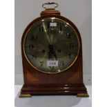 Medium mahogany circular mantel clock with satin wood decoration on brass bracket feet with key and