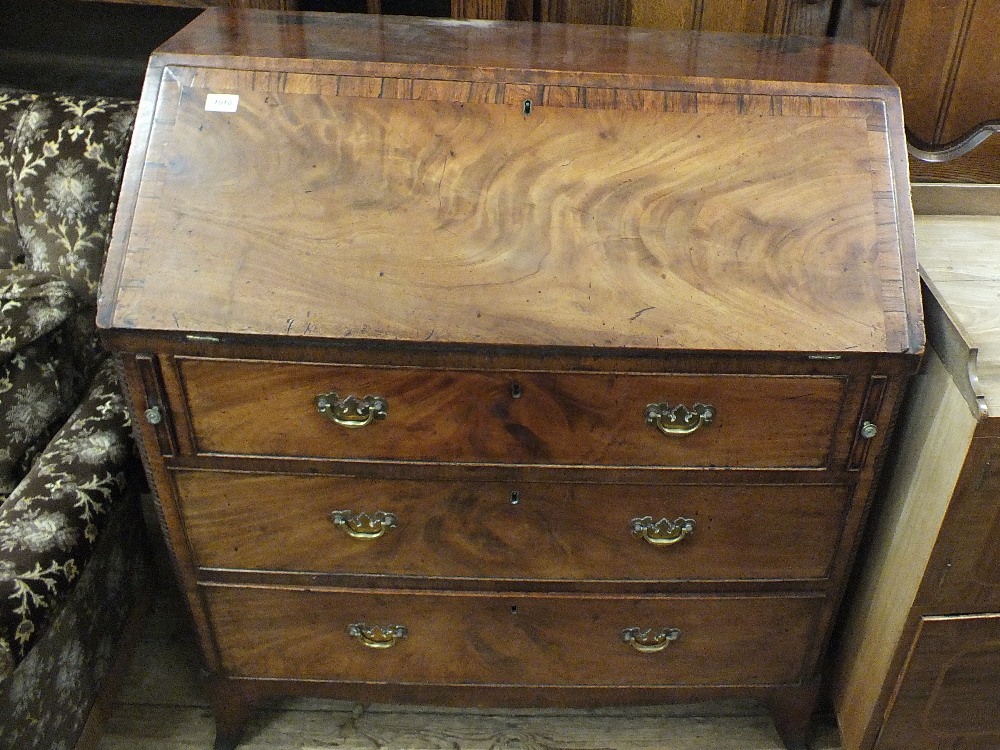 A Georgian mahogany and cross banded bureau with three drawers on bracket feet
