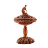 A carved nut lidded pedestal box with dog finial,