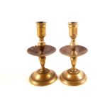 A pair of possibly 18th Century Dutch Heemskerk style brass candlesticks with mid drip pans,