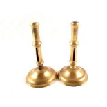 A pair of early 18th Century side ejector brass candlesticks on domed circular bases,