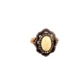 A yellow and white metal ring set with opal stone to centre with fancy border set with diamonds