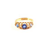 An 18ct gold ring set with three blue stones and two diamonds (one chipped),