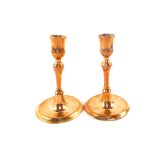 A pair of small 18th Century red brass candlesticks with tulip shaped sconces and dished circular