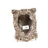 A silver heart shaped easel mirror with later added feet,