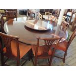 A large circular mahogany dining table with Lazy Susan and heat cover mats plus a set of eight