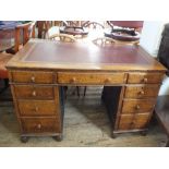 An oak nine drawer pedestal desk with red leather insert