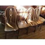 A set of four wheel back dining chairs