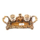 A 19th Century Rococo brass inkstand with central wax compartment and taperstick flanked by twin