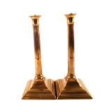 A pair of 18th Century seamed brass candlesticks with fluted cylindrical stems and engraved square