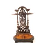 A late Victorian cast iron stick stand with decorative open work back plate having arched top and