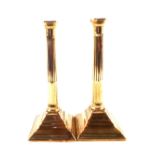 A pair of 18th Century brass candlesticks with fluted cylindrical stems and beaded square bases,