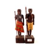 A pair of naturalistically carved wooden tribal figurers with cloth aprons