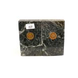 A pair of polished granite bookends with inlaid brass T star motifs