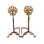 A pair of Arts and Crafts wrought iron and pierced brass floral medallion fire dogs on arched legs,