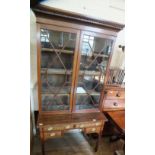 A mahogany Edwardian astral glazed bookcase with cross banding above a knee hole desk with four