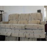 A modern three seater sofa in beige upholstery with poppy design and two matching armchairs