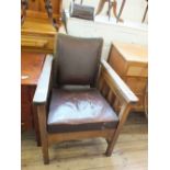 A 1920's oak and rexine upholstered barber's chair with adjustable back and chrome head rest
