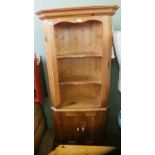 A pine two door and three shelved corner cupboard with curved back