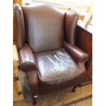A maroon leather wing back reclining arm chair on cabriole legs