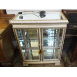 A white and gilt two door glazed display cabinet and a matching single drawer display cabinet