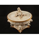 An unglazed porcelain lidded oval bowl with four cherub supports and mount
