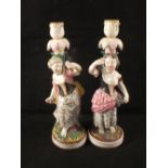 A pair of 19th Century polychrome figural candlesticks, each holding a bunch of grapes,