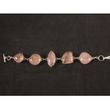 A white metal bracelet set with large rose quartz stones,