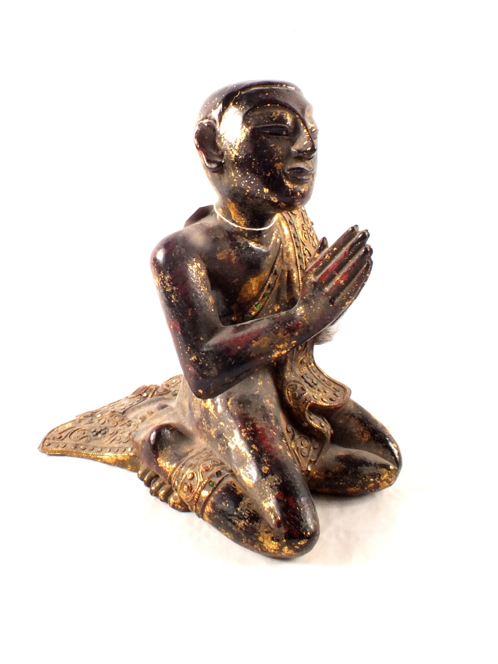 An Asian gilt decorated wooden praying figure with applied glass decoration,