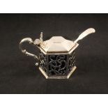 An octagonal pierced silver mustard with decorative handle and family crest,