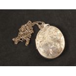 A large oval silver locket with engraved decoration on silver chain
