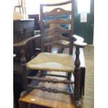 An elm ladder back elbow rocking chair with rush seat (as found)