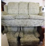 A modern wingback three seat settee with green floral covers and two matching armchairs