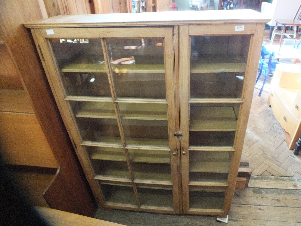 A large light oak glazed two door cupboard with adjustable shelves