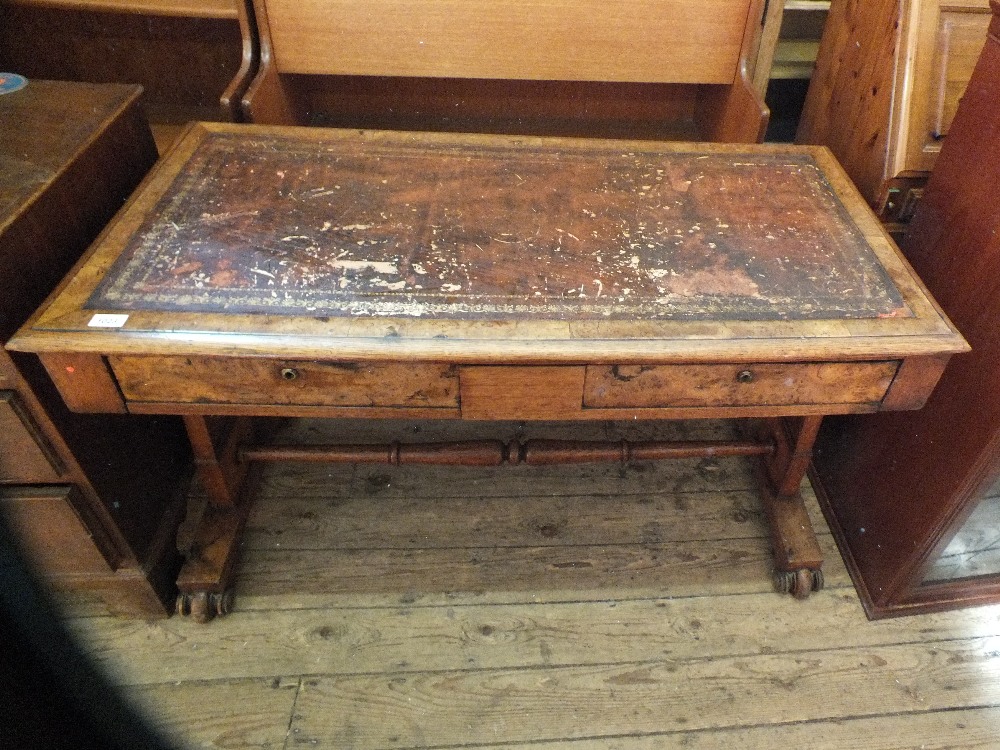 An oak and walnut veneer writing table with two drawers and tooled leather inset top on stretcher