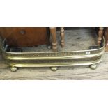 A Victorian brass fender with pierced fretwork on three ornamental feet