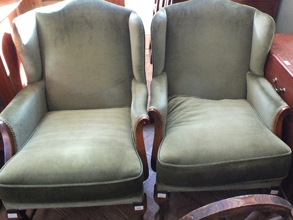 A pair of vintage wingback armchairs with pale green velour upholstery