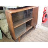 A combination oak glazed bookcase and single cupboard on legs