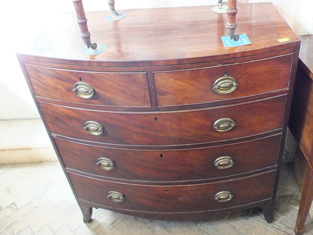 A flame mahogany bow fronted chest of short and three long drawers with metal handles on carved